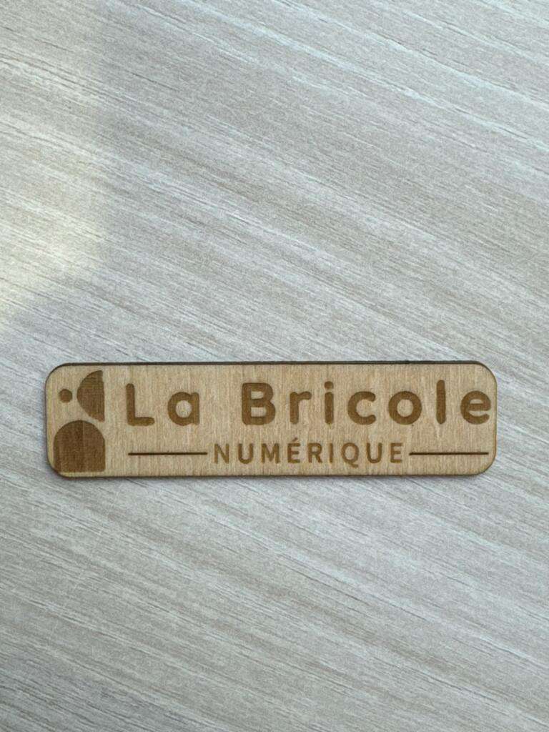 Logo de La Bricole Numérique gravé sur un petit morceau de bois rectangulaire